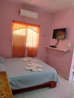 a bedroom with pink walls and a bed with a window at Central Rooms Bayahibe in Bayahibe