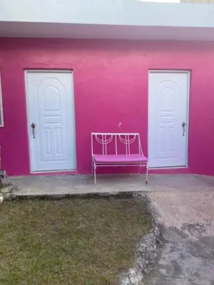 a pink wall with two doors and a purple bench at Central Rooms Bayahibe in Bayahibe