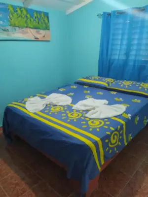 a blue bed with a blue and yellow bedspread at Central Rooms Bayahibe in Bayahibe