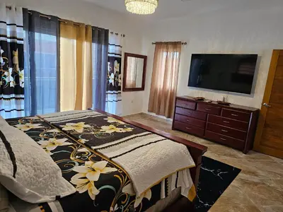 a bedroom with a bed and a flat screen tv at Villa Selina in Punta Cana