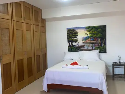 a bedroom with a white bed with a painting on the wall at Heavenly View in San Felipe de Puerto Plata