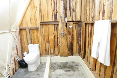 a bathroom with a toilet and wooden walls at NOMAD Domes at Salto Jimenoa, Jarabacoa in Jarabacoa