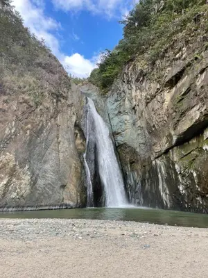 a waterfall on the side of a cliff with a body of water at NOMAD Domes at Salto Jimenoa, Jarabacoa in Jarabacoa