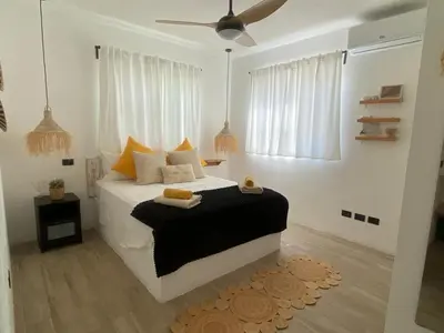 a bedroom with a large white bed with yellow pillows at Portitxol, fantástico apartamento in Bayahibe