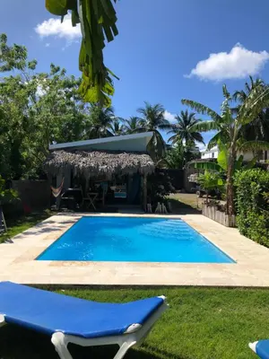 a blue swimming pool with a chair and a house at Sfeervolle studio in Encuentro Cabarete in Cabarete