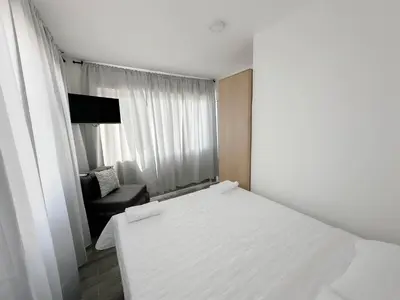 a white bedroom with a bed and a chair at La Yarolina in Punta Cana