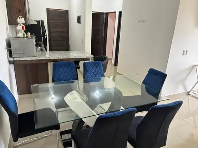 a glass dining room table with blue chairs at Chelsie 402 in Bayahibe