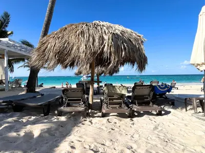 a group of chairs and an umbrella on the beach at BeachFront Apartament - Private Beach Access in Punta Cana