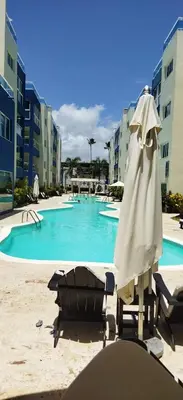 a pool with chairs and an umbrella in front of it at BeachFront Apartament - Private Beach Access in Punta Cana