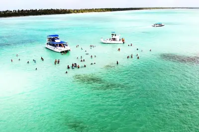 a group of people swimming in the ocean with boats at Tropical Deluxe 2 Bedroom Unit with Picuzzi in Punta Cana