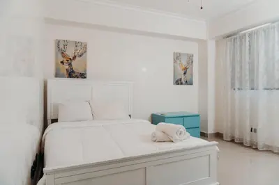 a white bedroom with a white bed and a window at Oceanfront 3 Bedroom With Jacuzzi and Pool in Santo Domingo