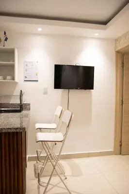 a room with two white chairs and a flat screen tv on the wall at Casa de Nini in Santo Domingo