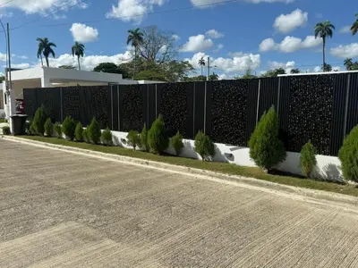 a fence next to a road with trees at villa green paradise in San Felipe de Puerto Plata