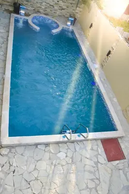 a large swimming pool with blue water and rocks at Villa lujosa con piscina bayaguana in Bayaguana
