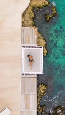 a woman is sitting in a box on a pier near the water at TRACADERO Beach Club & Holidays Rentals in Bayahibe
