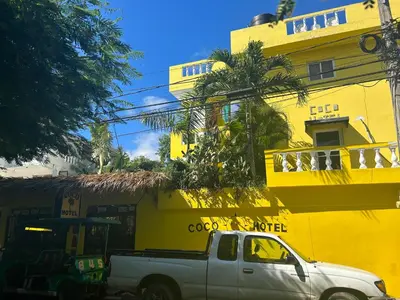 a white truck parked in front of a yellow building at Coco Hotel and Hostel in Sosúa