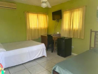 a room with two beds and a desk and a table at Coco Hotel and Hostel in Sosúa