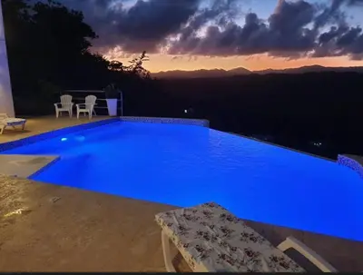 a large blue swimming pool with a sunset in the background at Apartamento panorámico vista al mar in Las Galeras