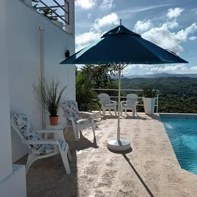 a blue umbrella sitting on a patio next to a pool at Apartamento panorámico vista al mar in Las Galeras