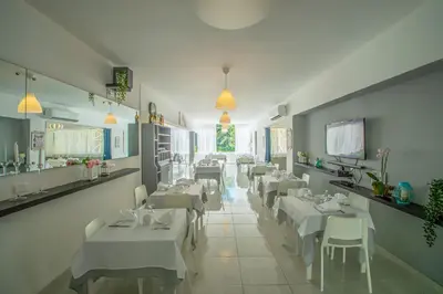 a dining room with white tables and white chairs at Hotel Plaza Europa in Sosúa