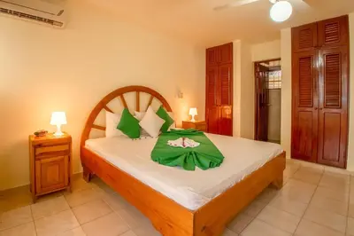 a bedroom with a bed with a green blanket on it at Hotel Plaza Europa in Sosúa