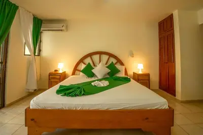 a bedroom with a large bed with a green blanket at Hotel Plaza Europa in Sosúa