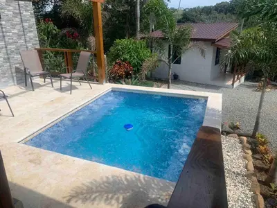 a small swimming pool with chairs and a house at Villa María Victoria, en Jarabacoa in Jarabacoa