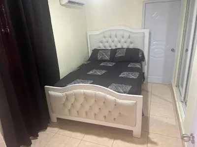 a bedroom with a white bed with black sheets at El anexos in Santiago de los Caballeros
