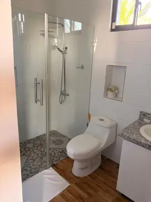 a white bathroom with a toilet and a shower at Hotel Vista al Morro in San Fernando de Monte Cristi