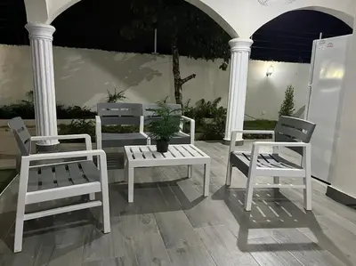 three white benches and a potted plant on a porch at Villa Familiar con Piscina cerca Av Ecológica in La Ureña