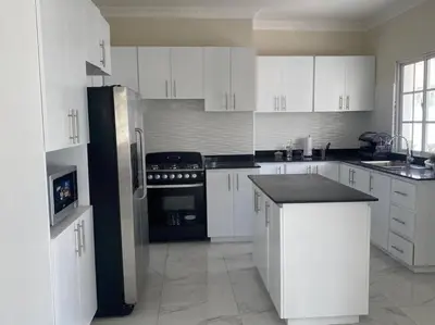 a kitchen with white cabinets and a black refrigerator at Villa Familiar con Piscina cerca Av Ecológica in La Ureña