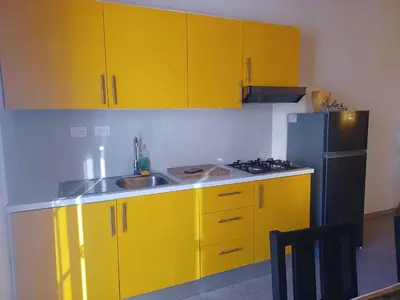 a yellow kitchen with a sink and a refrigerator at Tropical Doña Mayra apartahotel in Las Terrenas