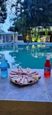 a plate of hot dogs on a table next to a swimming pool at Casa en Villa Marchena azua in Azua de Compostela