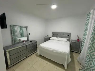 a bedroom with a white bed and a mirror at Casa en Villa Marchena azua in Azua de Compostela