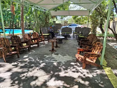 a group of wooden chairs and tables under a tent at Habitación doble Villa Marchena Azua in Azua de Compostela