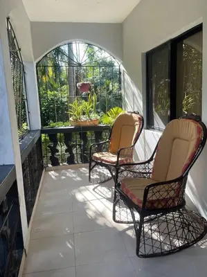a porch with two chairs and a table on a balcony at Country home in the hills of Samana in Santa Bárbara de Samaná