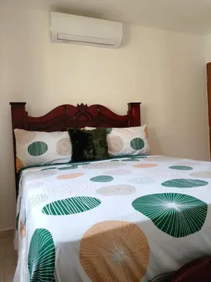 a bed with a white and green blanket on it at Caleta in La Romana