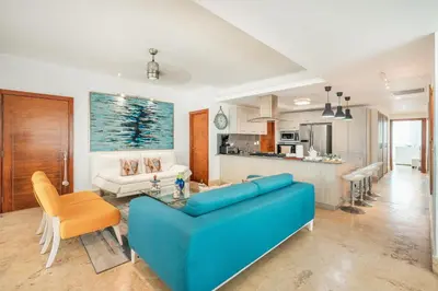 a living room with a blue couch and a kitchen at 3BR apartment with beach access and ocean view in Juan Dolio