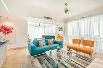 a living room with a blue couch and a table at 3BR apartment with beach access and ocean view in Juan Dolio