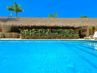 a resort with a large swimming pool with a thatch roof at La Curadiña - Encuentro Surf Resort in Cabarete