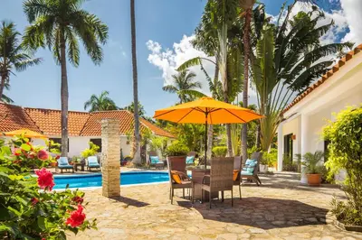 a patio with an umbrella and chairs next to a pool at Garden By The Sea in Sosúa