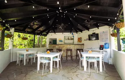 a patio with tables and chairs and a kitchen at Garden By The Sea in Sosúa