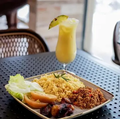 a plate of food with rice and a drink on a table at Playa Palmera Ocean View in Punta Cana