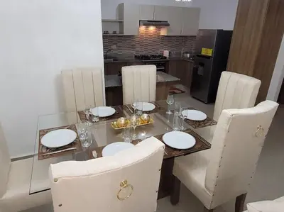 a dining room table with white plates and chairs at El mejor alojamiento en Santiago in Santiago de los Caballeros