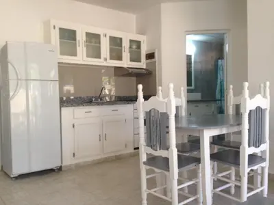 a kitchen with a table and a white refrigerator at Cita del Sol City Apartments in Cabarete