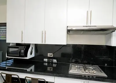 a kitchen with white cabinets and a stove and a microwave at Apartamento moderno de una habitación in San Pedro de Macorís