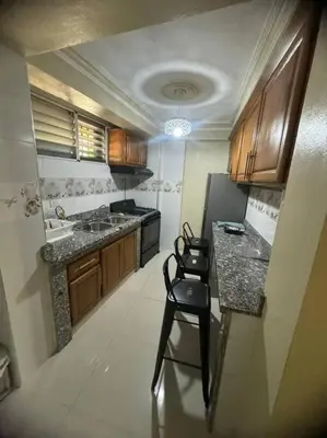 a kitchen with a counter and two chairs in it at Oasis en la Sultana del Este in San Pedro de Macorís