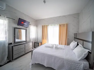 a bedroom with a white bed and a television at 8br Private Villa In Sosa - 2 Mins From Nightlife in Sosúa
