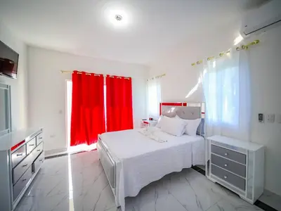 a bedroom with a white bed and a red curtain at 8br Private Villa In Sosa - 2 Mins From Nightlife in Sosúa