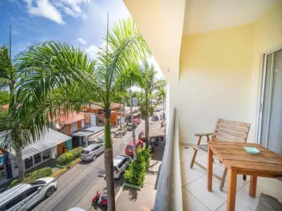 a balcony with a wooden table and a palm tree at 2BR Luxury Apartment in Heart Of Nightlife Area in Sosúa